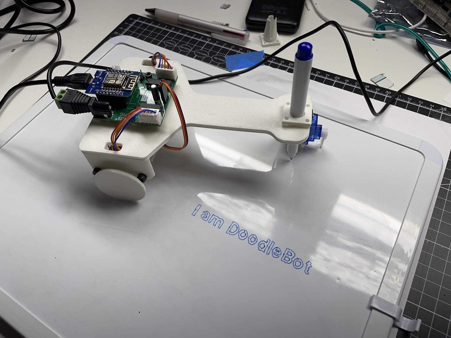 Photo of DoodleBot v2, with a drawing on a whiteboard